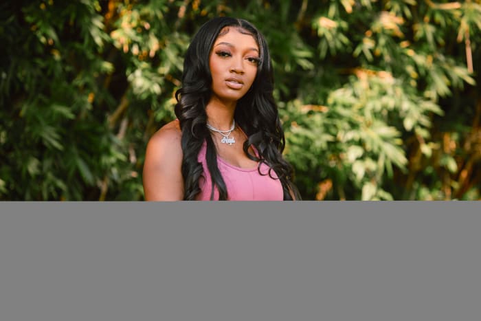 Angel Reese models pink Reebok apparel.